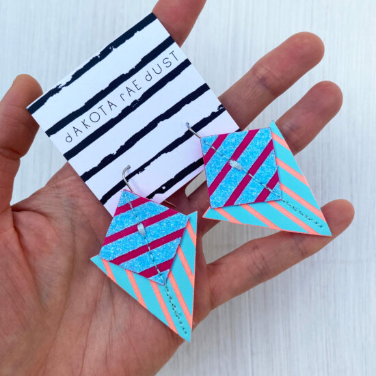 A colourful pair of graphic stripe earrings held in an open hand