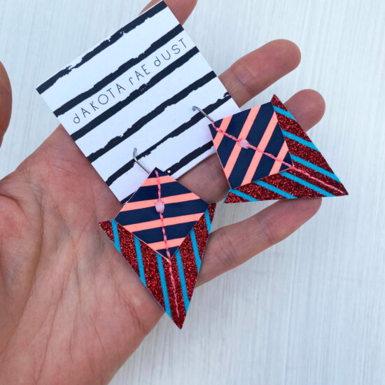 A colourful pair of graphic stripe earrings held in an open hand