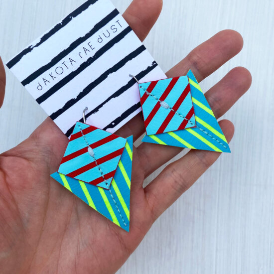 A colourful pair of graphic stripe earrings held in an open hand