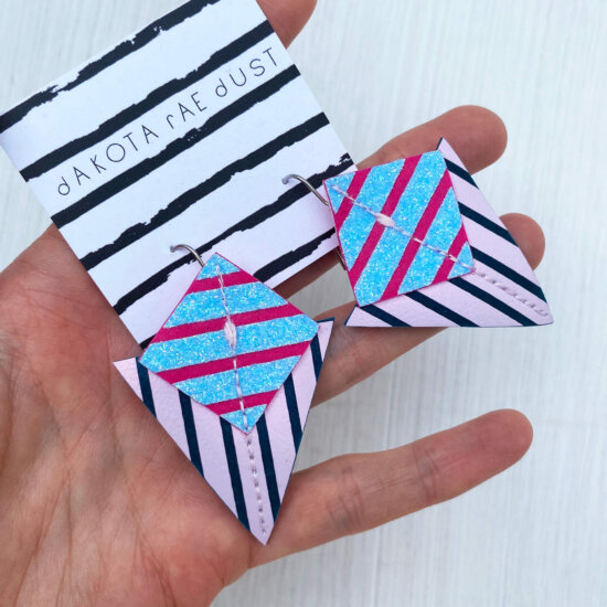 A colourful pair of graphic stripe earrings held in an open hand