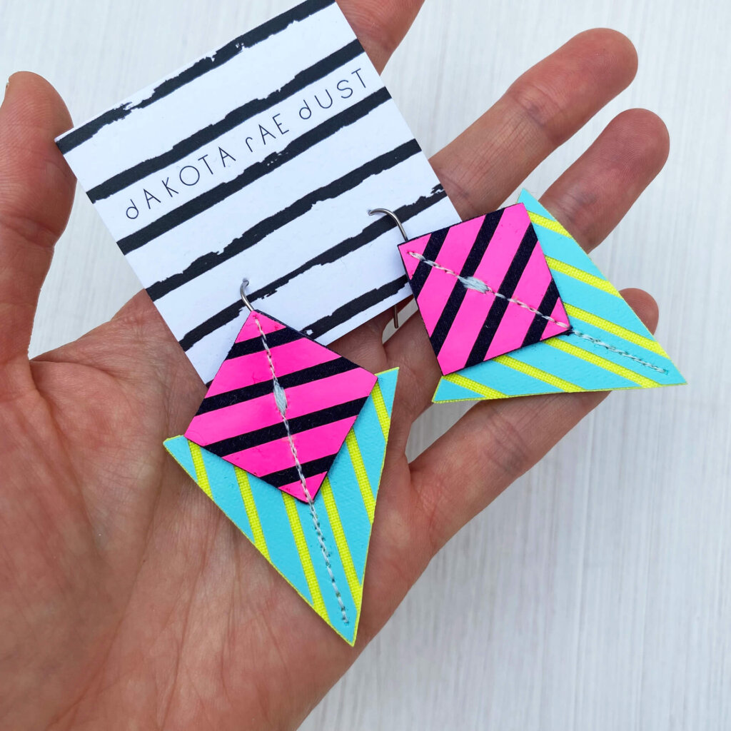 A colourful pair of graphic stripe earrings held in an open hand