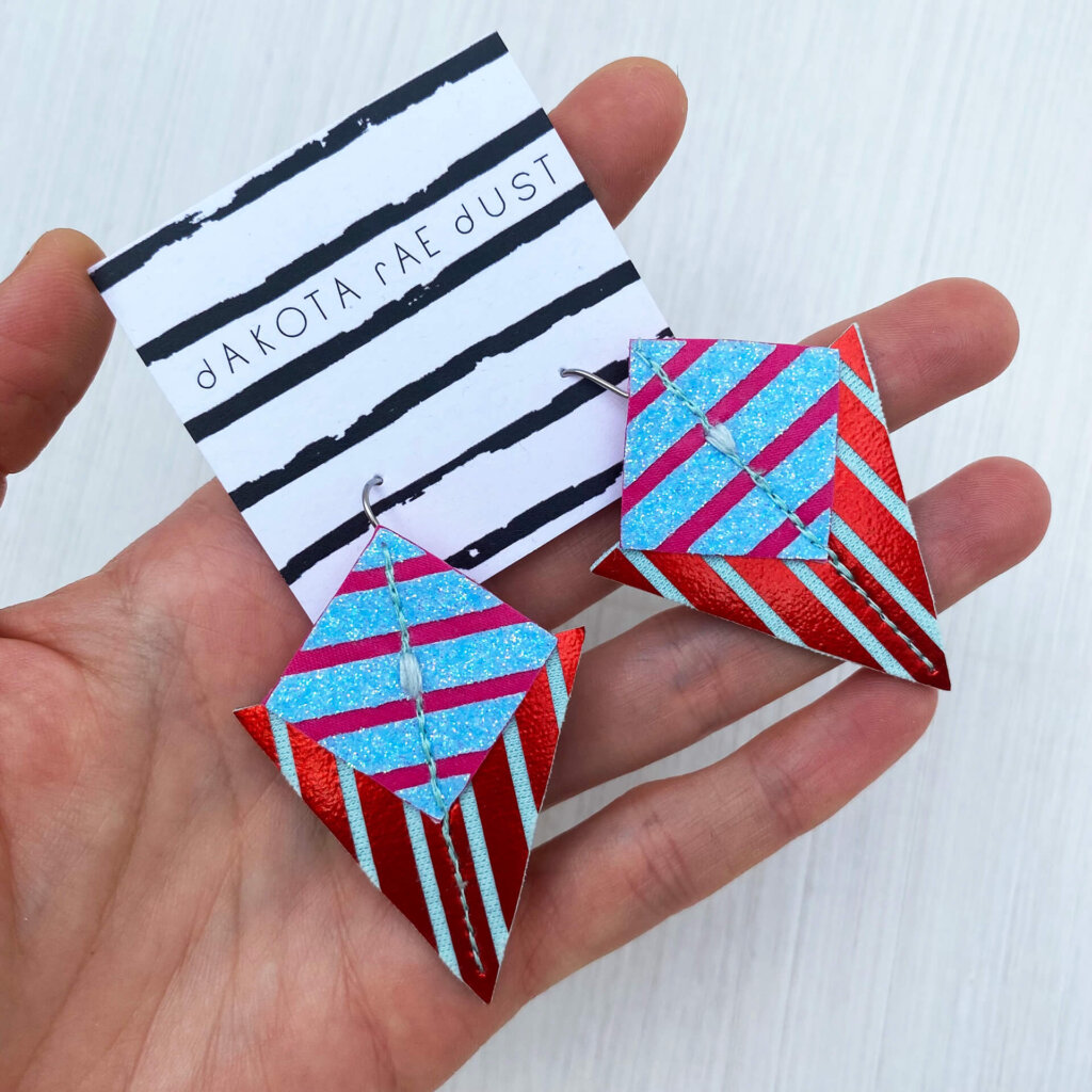 A colourful pair of graphic stripe earrings held in an open hand