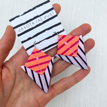 A colourful pair of graphic stripe earrings held in an open hand