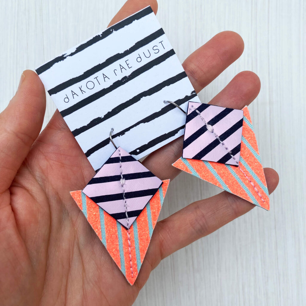 A colourful pair of graphic stripe earrings held in an open hand