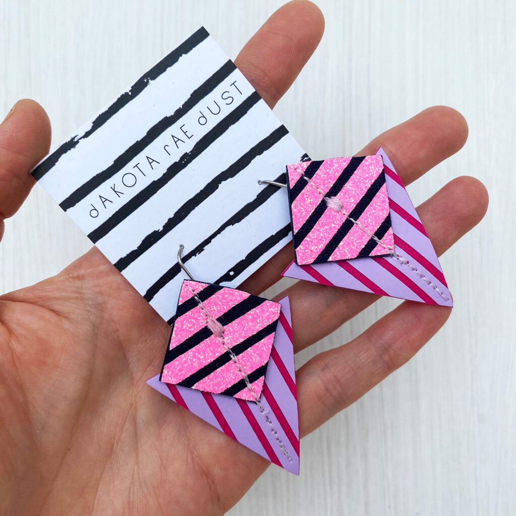 A colourful pair of graphic stripe earrings held in an open hand