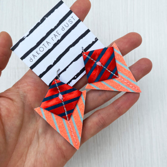 A colourful pair of graphic stripe earrings held in an open hand