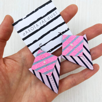 A colourful pair of graphic stripe earrings held in an open hand