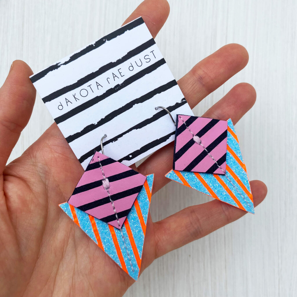 A colourful pair of graphic stripe earrings held in an open hand