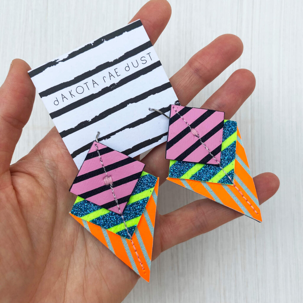 A colourful pair of graphic stripe earrings held in an open hand